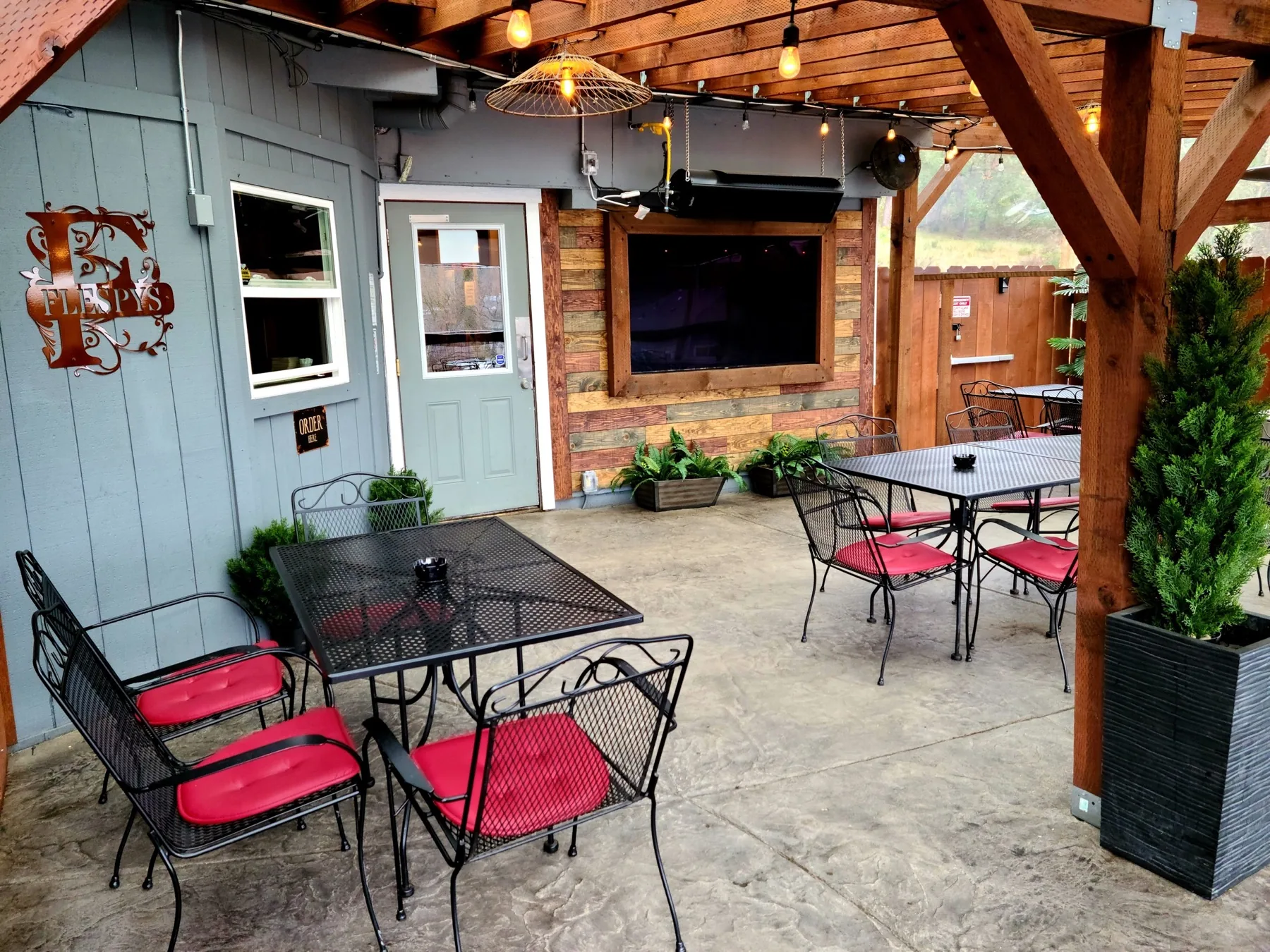 Covered patio seating, string lights, and television at Flespy’s